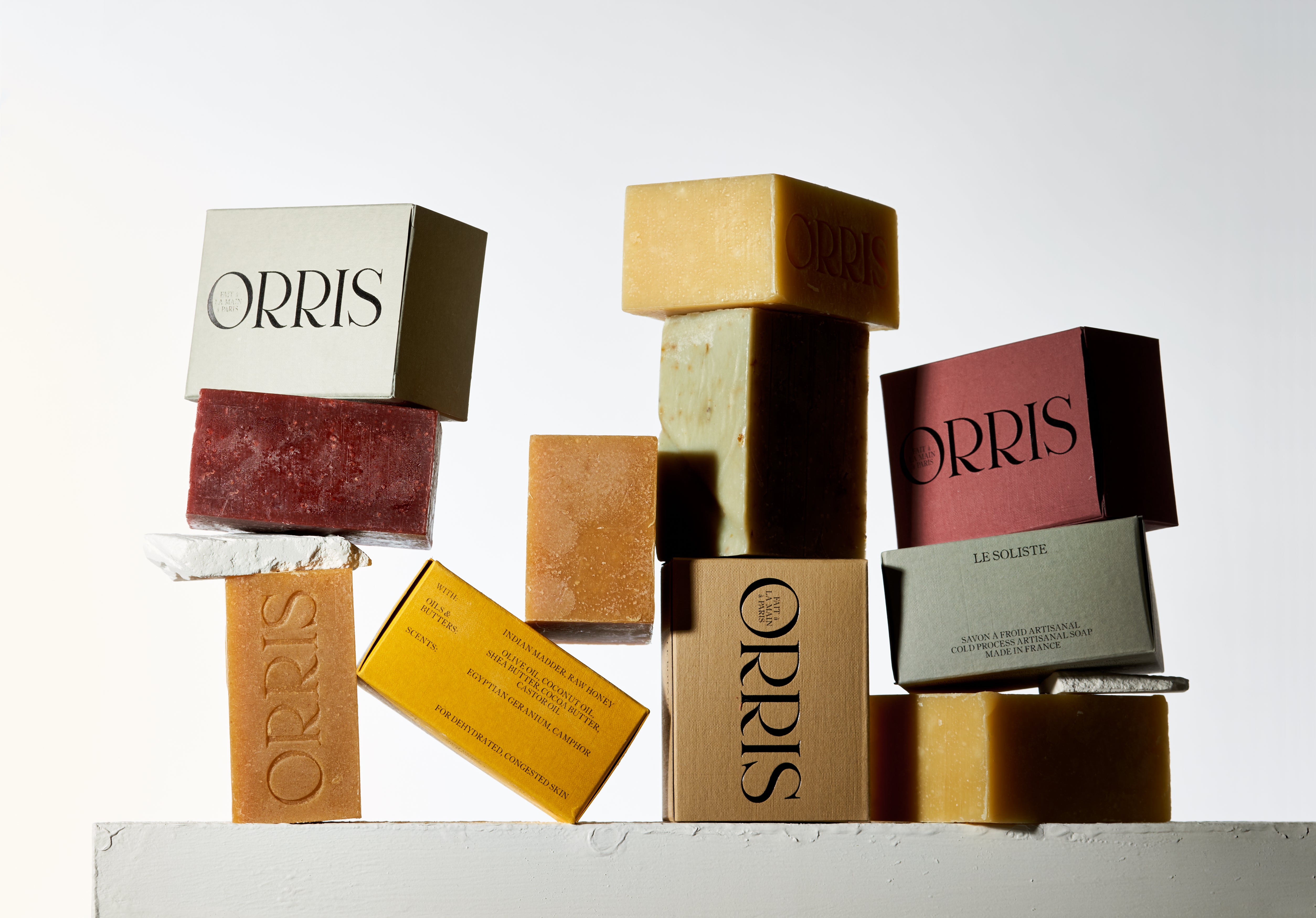 A collage of all Orris Cleansing Bars and their respective packages stacked into jumbled towers.