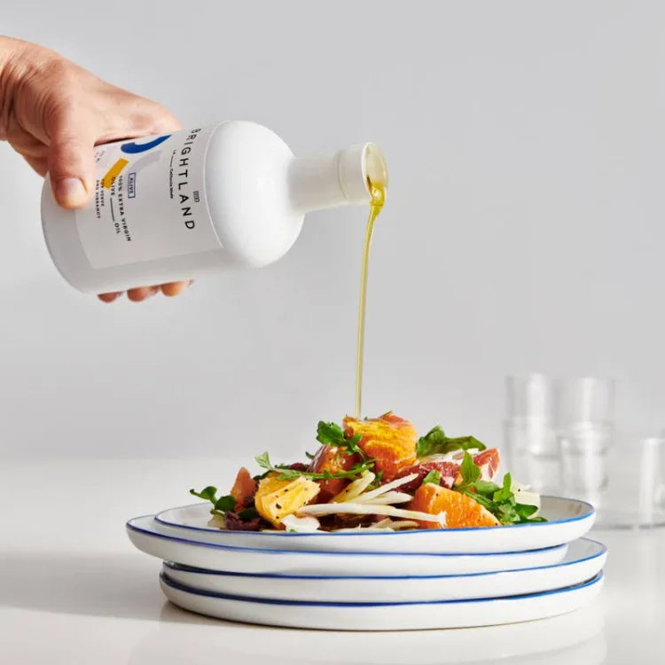 Brightland Cold Pressed California Olive Oil Alive being poured onto a salad