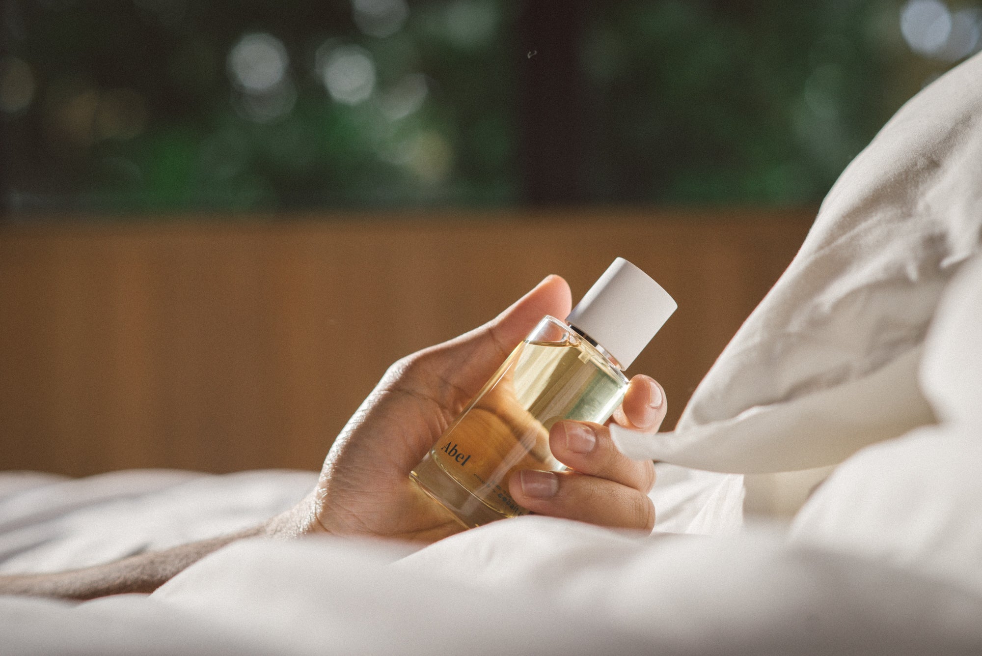 Abel Cobalt Amber held in a man's hand amongst a bed of pillows.
