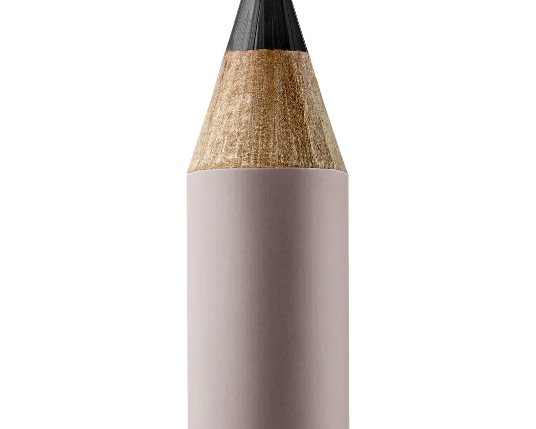 A sharpened Manasi 7 Lip and Eye Definer Petunia pencil showing the charcoal black color. The pencil itself is dark pink.
