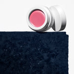 Manasi 7 All Over Colour dianthus jar and screw on top placed on a dark blue concrete block.