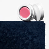 Manasi 7 All Over Colour dianthus jar and screw on top placed on a dark blue concrete block.