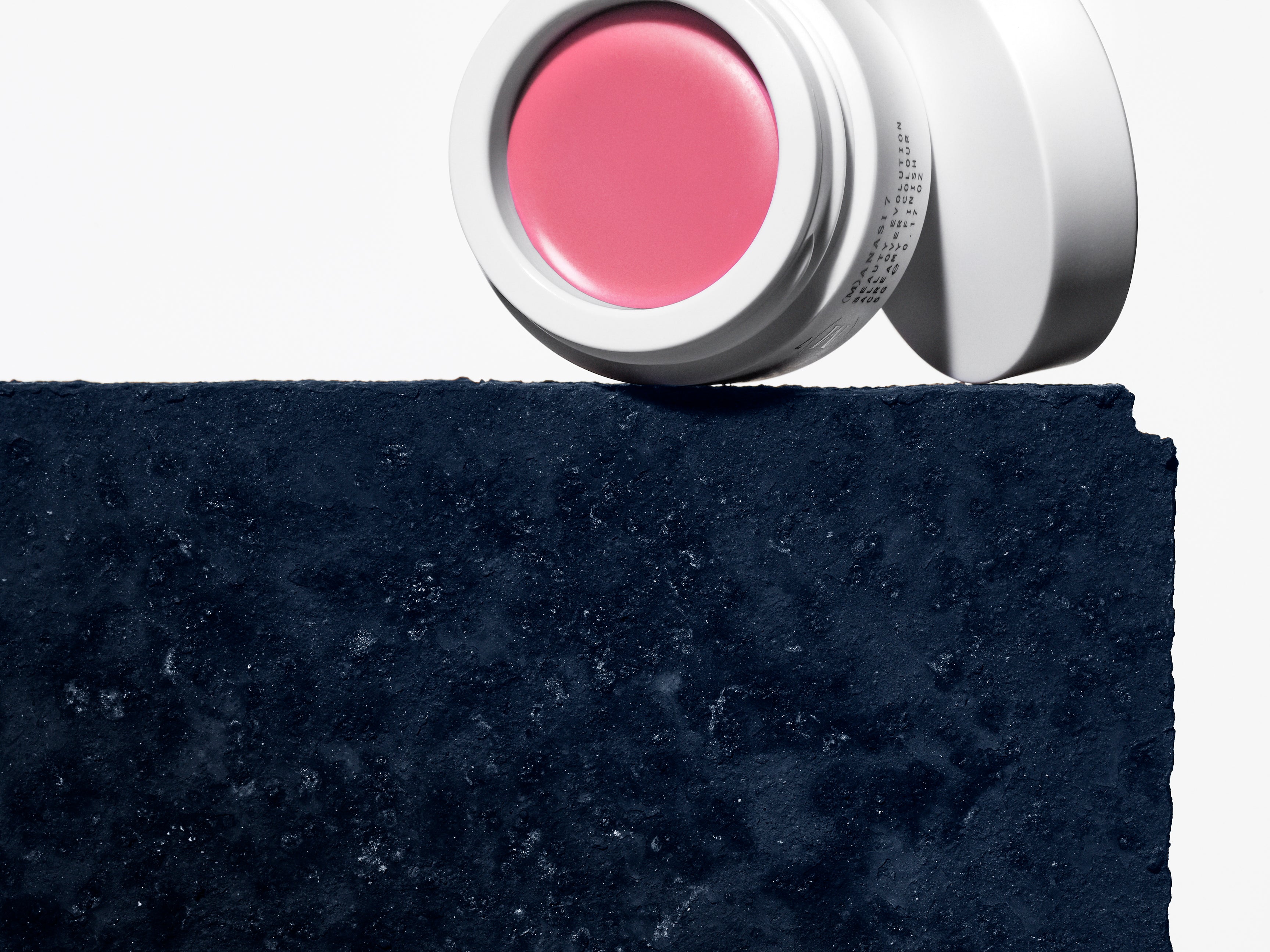 Manasi 7 All Over Colour dianthus jar and screw on top placed on a dark blue concrete block.