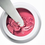 Manasi 7 All Over Colour dianthus in its white compact jar with a makeup brush dipped inside.