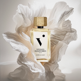 A bottle of Comme Un Gante gracefully set within a paper flower sculpture under soft studio lighting.