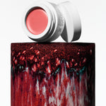 Manasi 7 All Over Colour Furusato in its white compact jar and screw on top placed on a red clay vase.