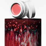Manasi 7 All Over Colour Furusato in its white compact jar and screw on top placed on a red clay vase.