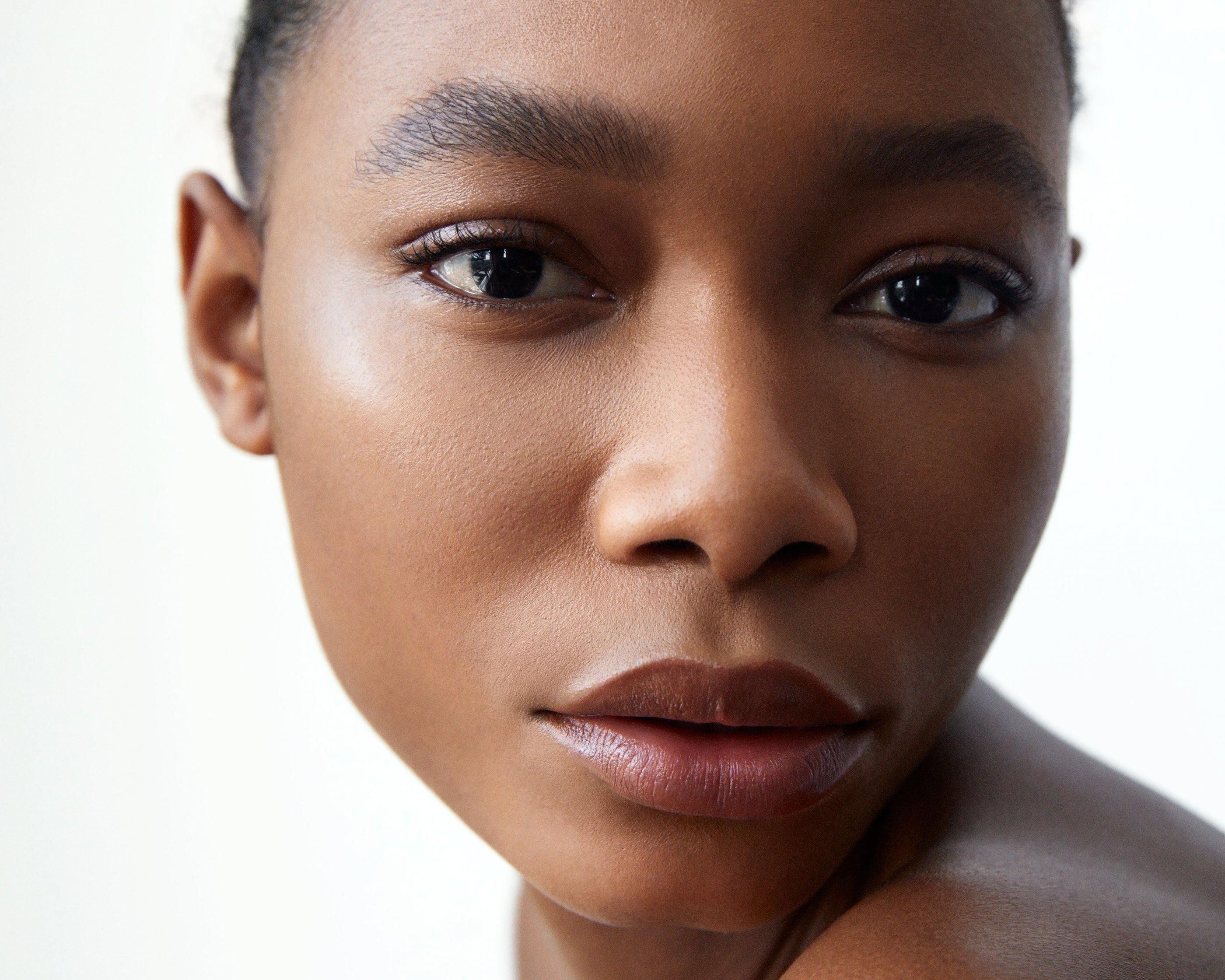 A close-up of a woman with dark complexion wearing Manasi 7 Silk Finish Powder, showcasing its translucent semi-matte finish.