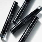 A grouping of Manasi 7 Obsidian Mascaras in a black glass tube with white branding text and a screw-on mascara wand top.