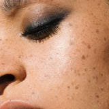 Close-up of a woman with medium complexion wearing Manasi 7 Obsidian Mascara on her lashes and eyelids as eyeliner.