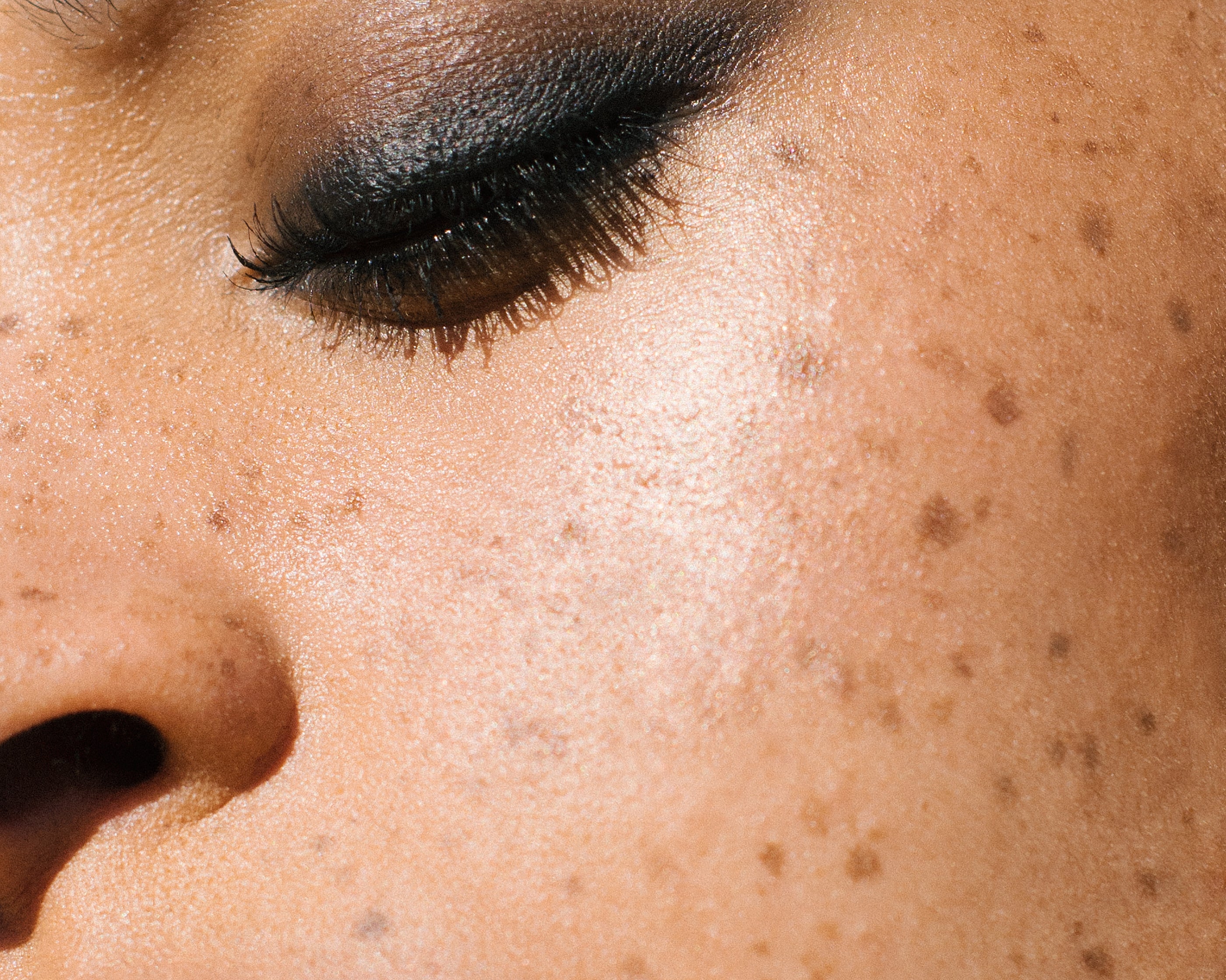 Close-up of a woman with medium complexion wearing Manasi 7 Obsidian Mascara on her lashes and eyelids as eyeliner.