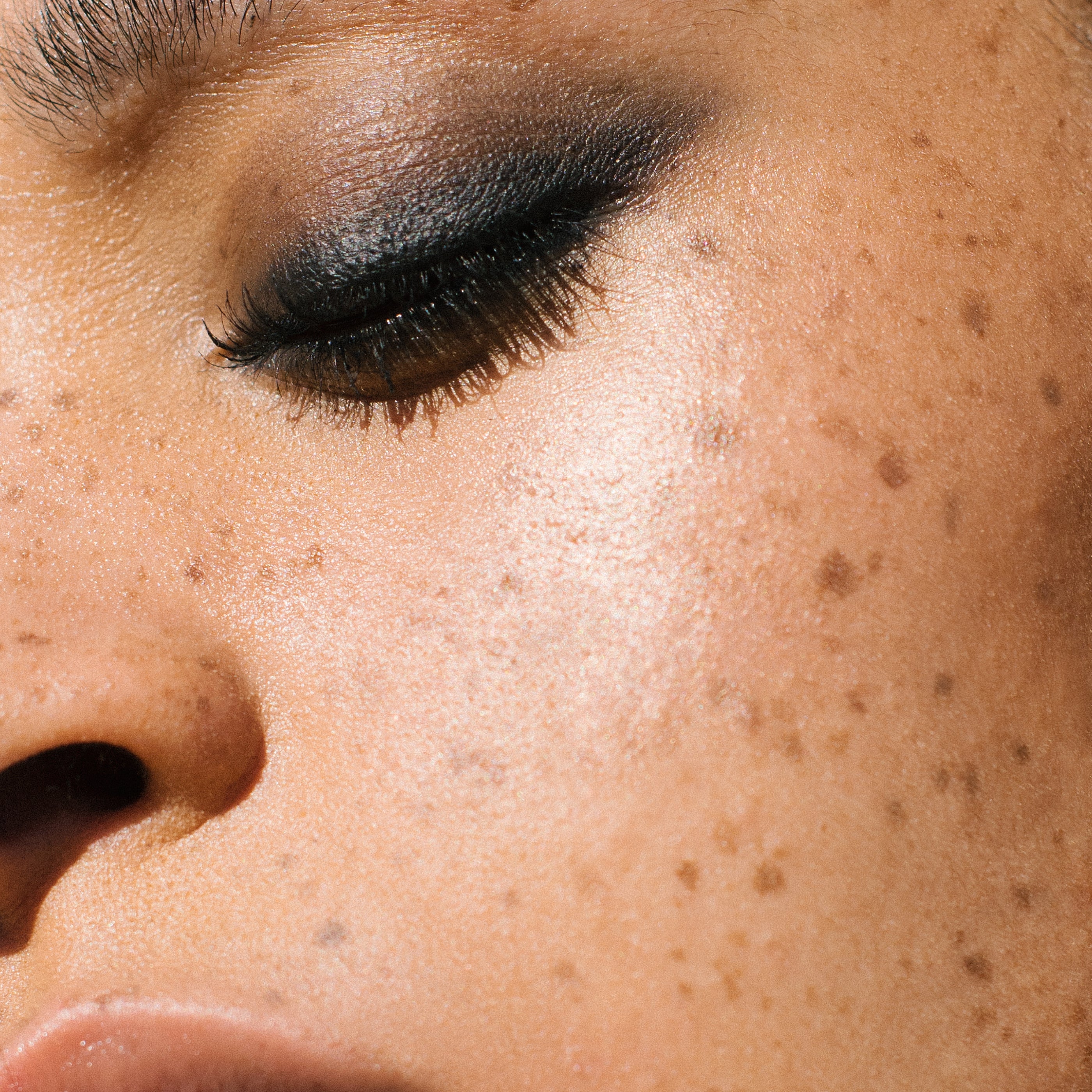 Close-up of a woman with medium complexion wearing Manasi 7 Obsidian Mascara on her lashes and eyelids as eyeliner.