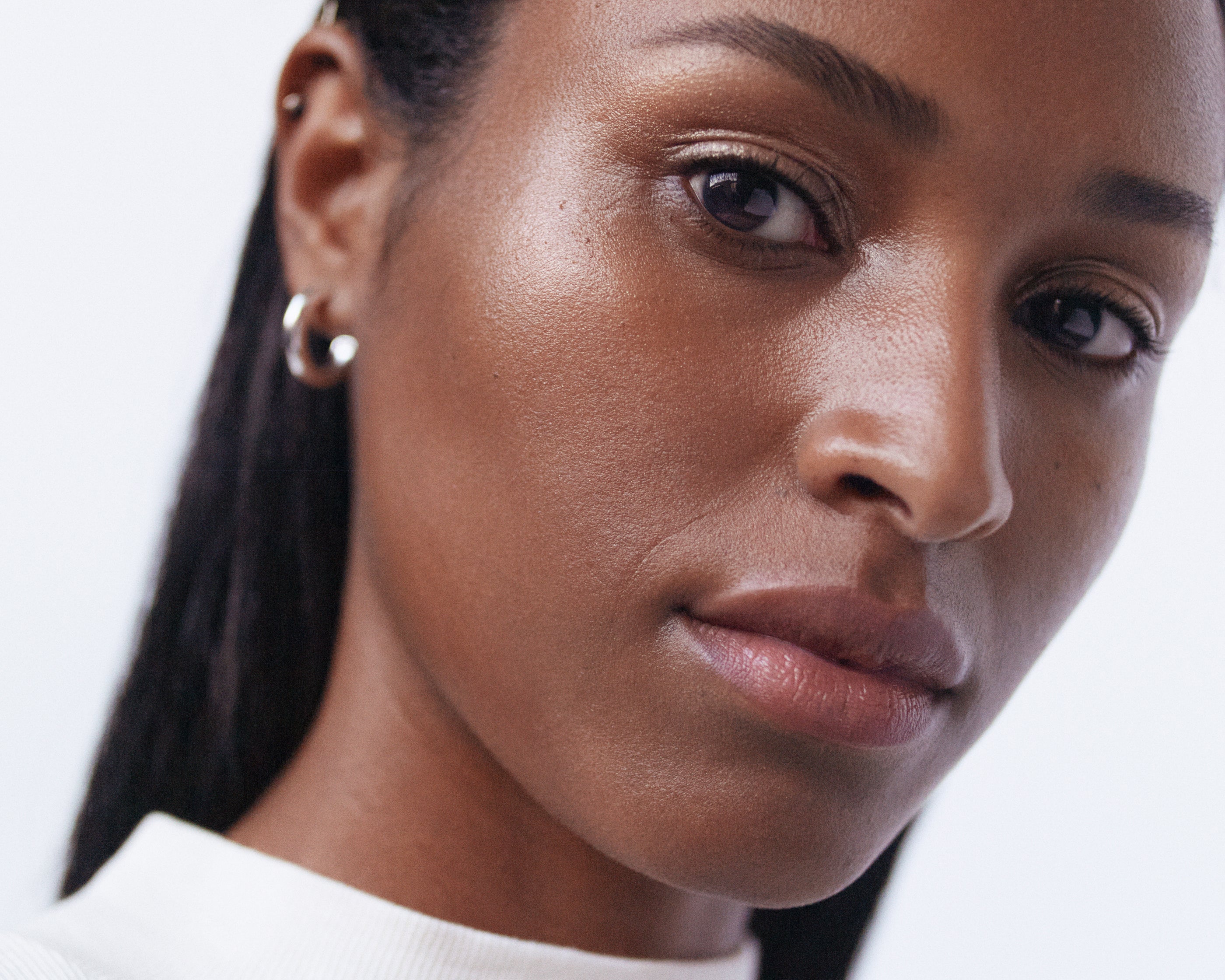 A woman with a dark complexion showcasing the radiant finish of Manasi 7 Strobelighter Heliconia.