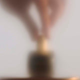 
  
  Osmé Fragrance PIRYTE showing hands placing the perfume on a counter after use.
  
