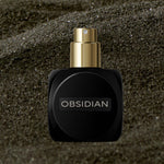 
  
  Black Osmé Fragrance Obsidian perfume bottle on sand with cap off
  
