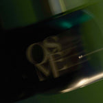 
  
  Osmé Fragrance TURMALI in motion displaying movement on a green background.
  
