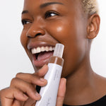 
  
  Ere Perez Oat Milk Foundation Mocha on a woman with dark complexion and neutral undertones holding Ere Perez Oatmilk Foundation.
  
