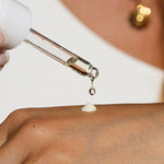 
  
  Close-up of a dropper applying a drop of Ere Perez Guava Gradual Tan to mix with Ere Perez Moringa All Beauty Cream to skin.
  
