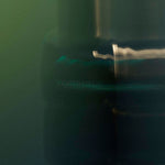 
  
  Osmé Fragrance TURMALI in blurred movement in a green background and reflection.
  
