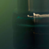 
  
  Osmé Fragrance TURMALI in blurred movement in a green background and reflection.
  
