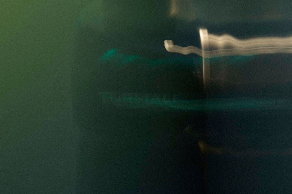 
  
  Osmé Fragrance TURMALI in blurred movement in a green background and reflection.
  
