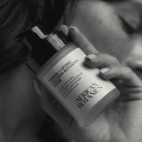 
  
  Hand holding a bottle of African Botanics Firming + Lifting Collagen Activator Serum with blurred background
  

