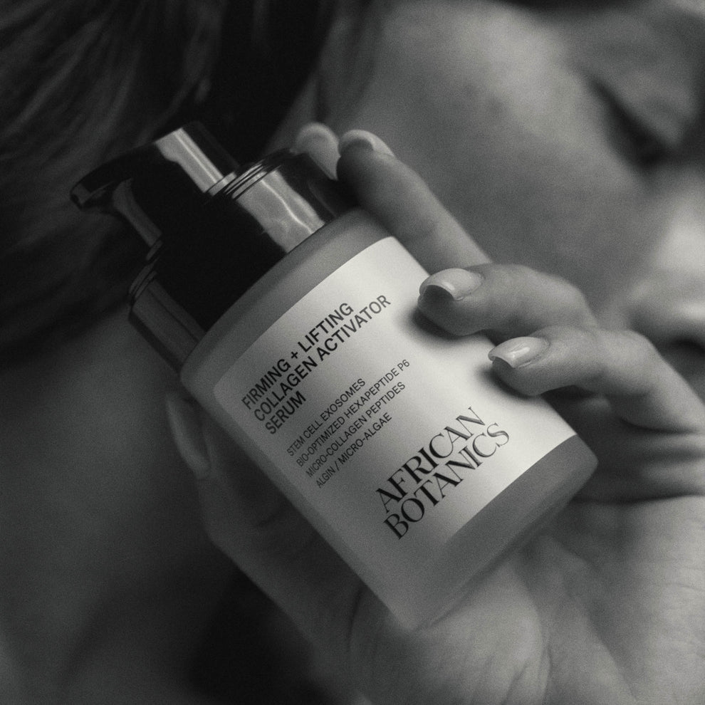 
  
  Hand holding a bottle of African Botanics Firming + Lifting Collagen Activator Serum with blurred background
  
