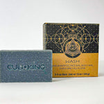 
  
  Cult + King's dark blue Shampoo Bar with an embossed logo next to its abstract patterned black and cardboard package.
  

