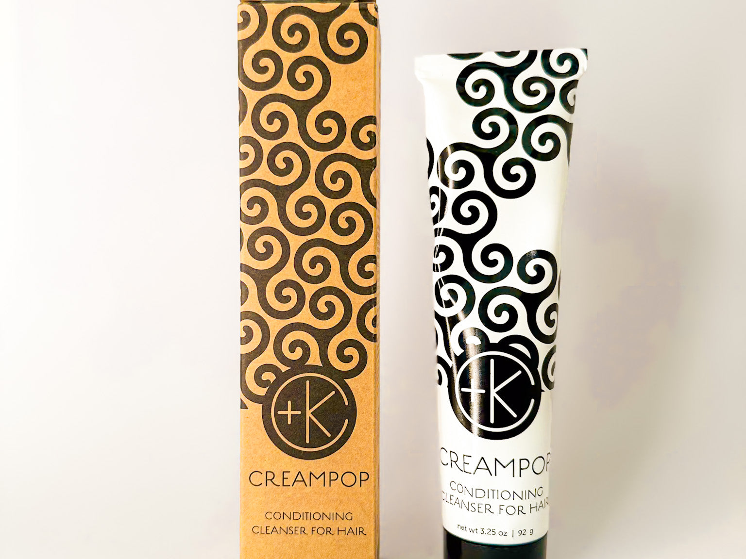 
  
  Cult + King CREAMPOP mini white tube with a black swirl-pattern, screw-on cap, and matching cardboard package.
  
