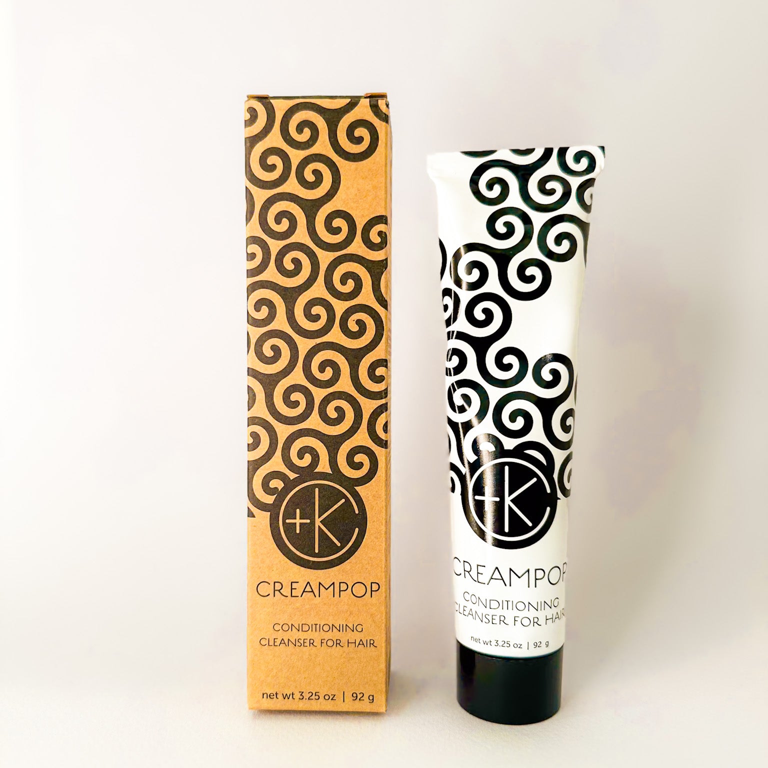 
  
  Cult + King CREAMPOP mini white tube with a black swirl-pattern, screw-on cap, and matching cardboard package.
  
