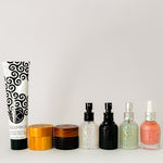 
  
  Cult + King mini haircare products in a swirl tube, bamboo jars, and assorted textured glass bottles with pumps and droppers.
  
