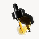
  
  Black dropper bottle with plum beauty oil on a white background
  
