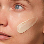 
  
  A creamy, ivory-colored swatch of Omorovicza Rejuvenating Night Cream on a woman's cheek.
  
