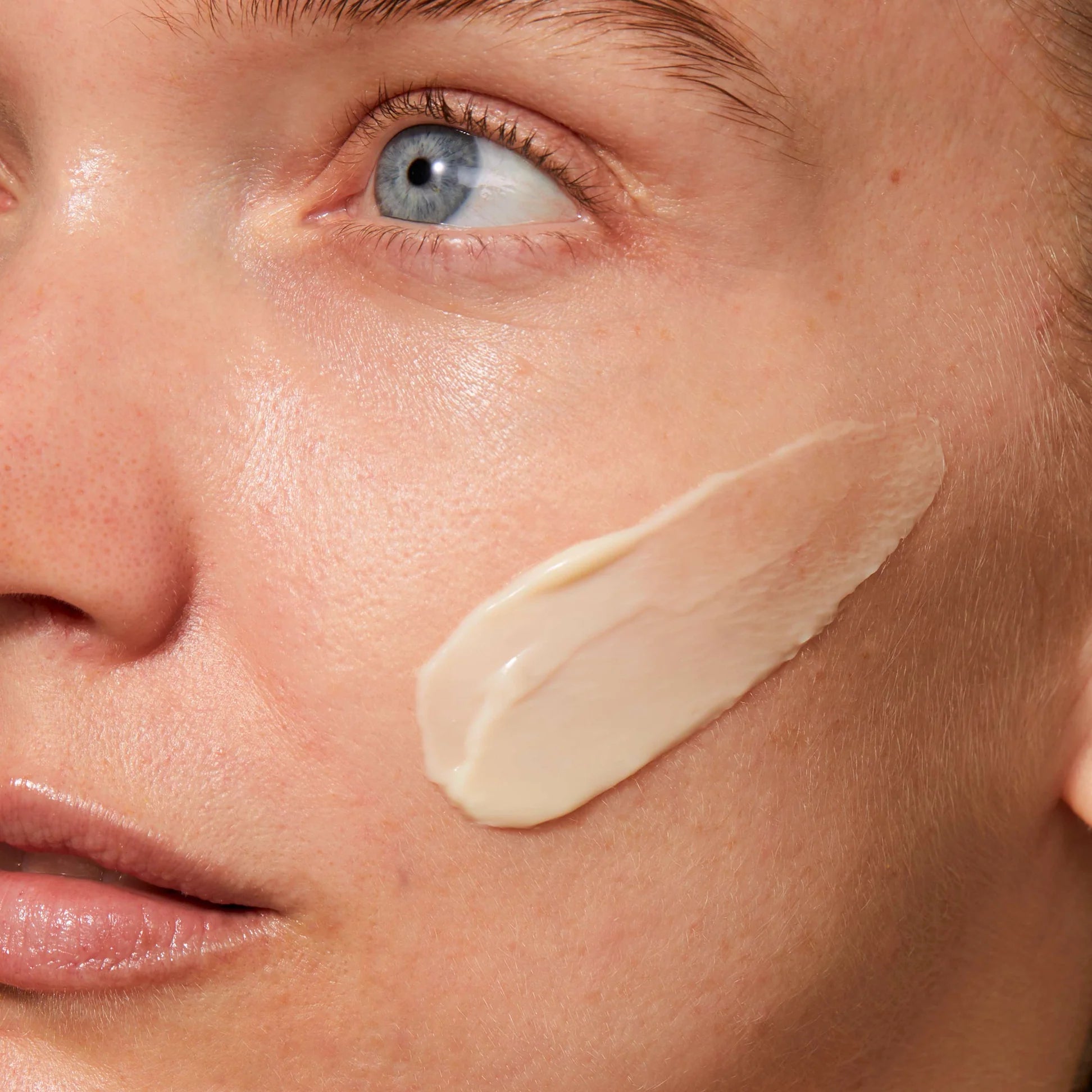 
  
  A creamy, ivory-colored swatch of Omorovicza Rejuvenating Night Cream on a woman's cheek.
  
