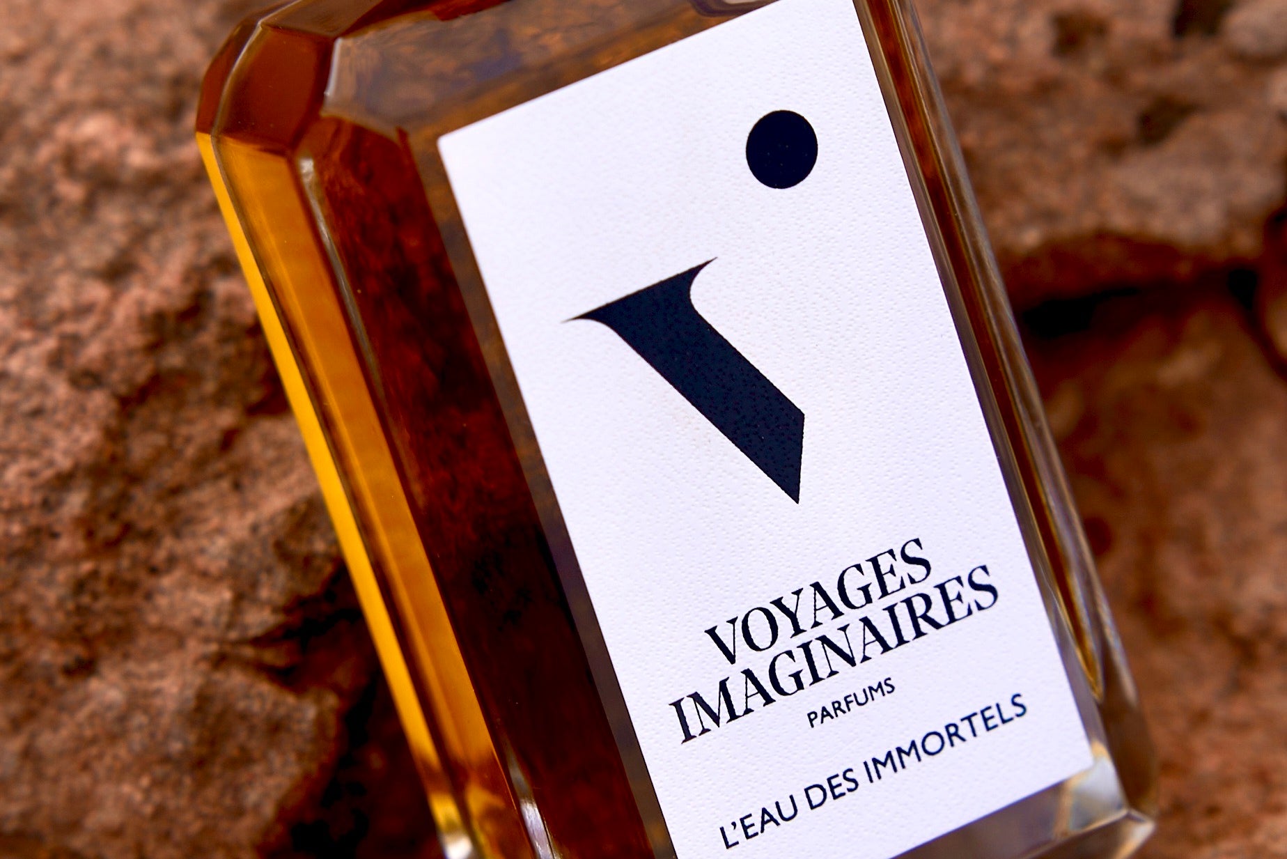 
  
  L'eau Des Immortels rested on red rocky ground within a warm desert terrain.
  
