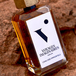 
  
  L'eau Des Immortels rested on red rocky ground within a warm desert terrain.
  
