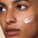 
  
  An unblended swatch of Omorovicza Cushioning Day Cream on a woman's cheek.
  

