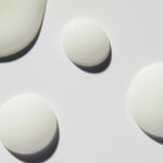 
  
  Close-up droplets of Omorovicza Even Tone Serum show its light, creamy consistency and white color.
  
