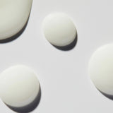 
  
  Close-up droplets of Omorovicza Even Tone Serum show its light, creamy consistency and white color.
  
