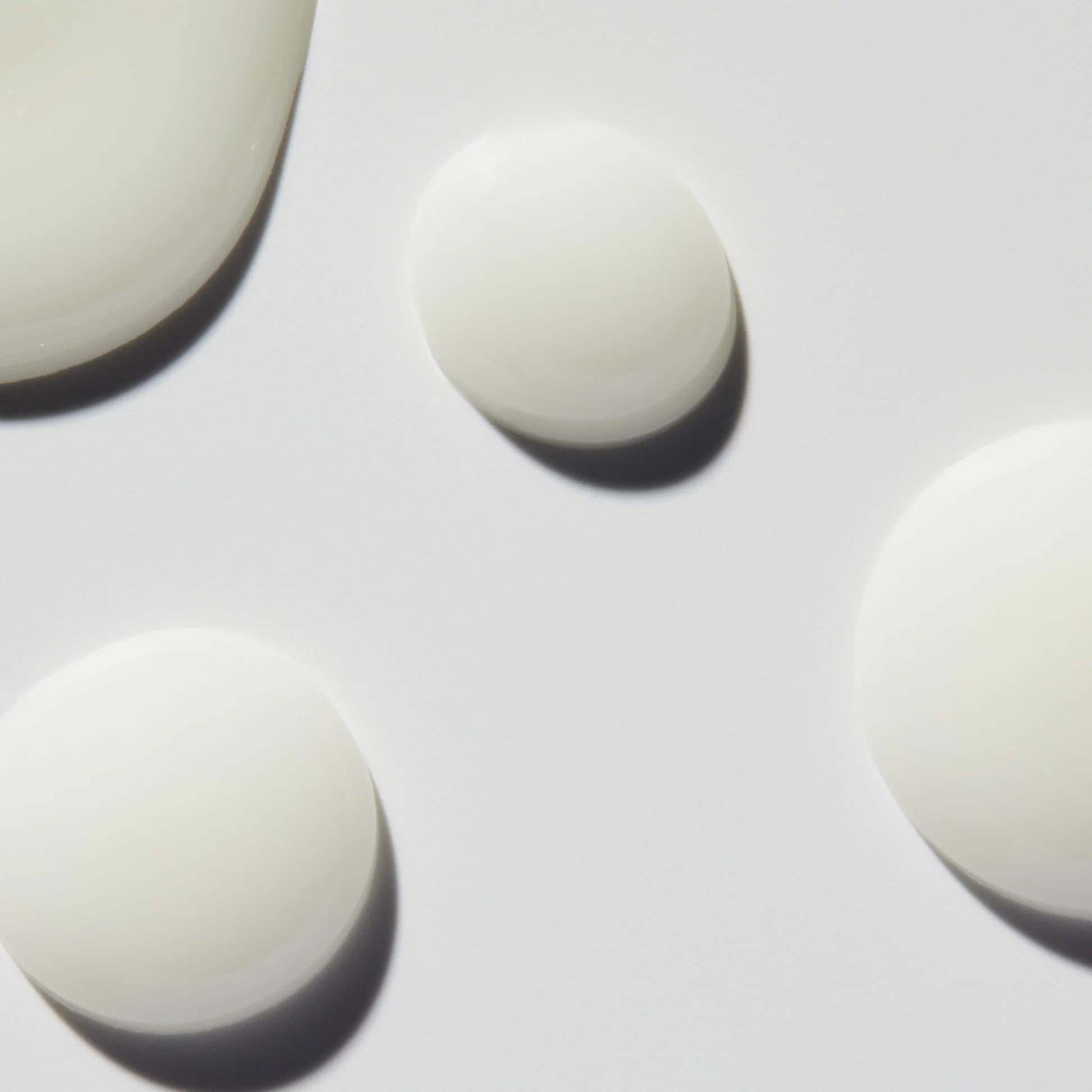 
  
  Close-up droplets of Omorovicza Even Tone Serum show its light, creamy consistency and white color.
  
