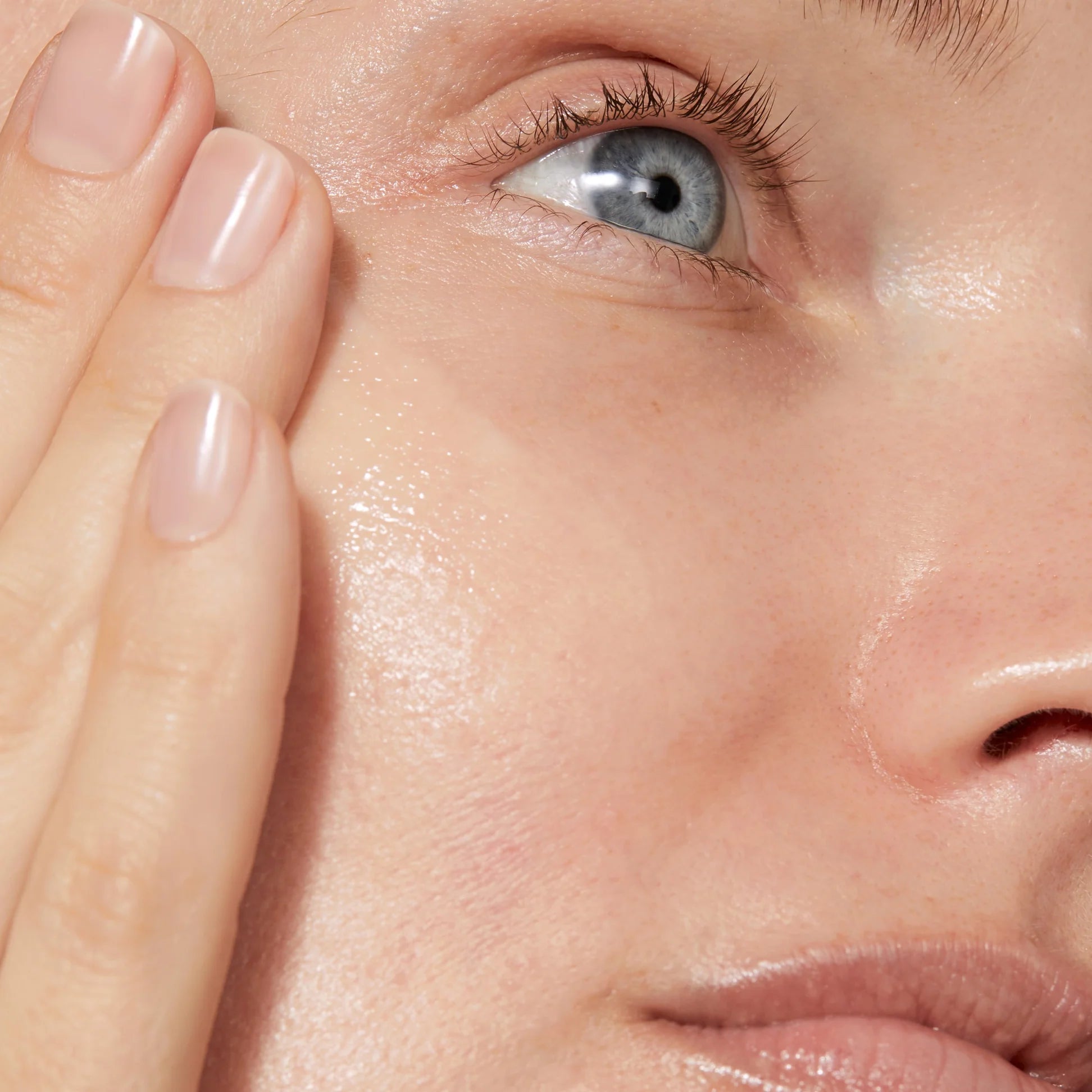 
  
  A woman smoothing Omorovicza Even Tone Serum into her cheek area.
  
